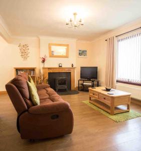 a living room with a couch and a tv at Ardmore Holiday Cottage in Trumpan +6 photos