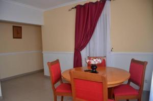 comedor con mesa de madera y sillas rojas en La Residence Sarah, en Douala