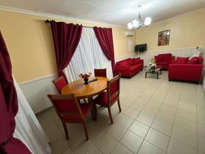sala de estar con mesa y sofás rojos en La Residence Sarah, en Douala