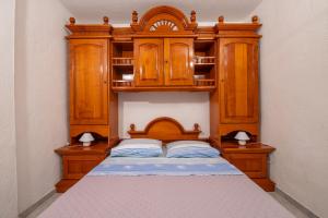a bed with a wooden headboard and wooden cabinets at Apartments Damjanic Jerko in Vrboska
