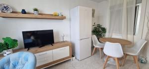 ein Wohnzimmer mit Fernseher und Tisch und Stühlen in der Unterkunft BENIDORM, Las Damas, primera línea de playa de Levante in Benidorm