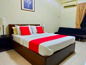 a bedroom with a large bed with red and white pillows at Capital O Suria Urban Escape in Kampong Selemat