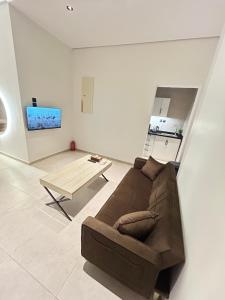 a living room with a brown couch and a table at NOOR iNN , Prime Location, SelfEntry in Medina