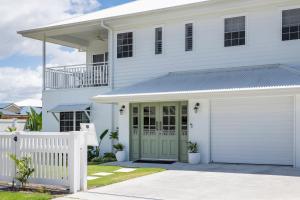 a white house with a green garage door at Biirinba in Yamba