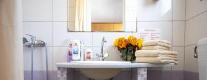 a bathroom sink with a vase of yellow flowers on it at Stefanie Studios in Egina