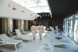 a man and woman walking through a room with white chairs at Le Berceau de La Source in Bagnères-de-Bigorre
