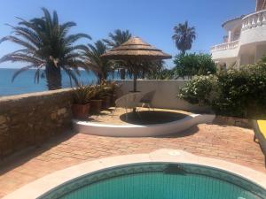 a swimming pool in front of a resort with the ocean at Beach front/waterside apartment in Luz