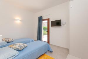 a bedroom with two beds and a tv on the wall at Domo Davide in San Teodoro
