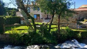 a house with trees and a river in front of it at O Relax do Río - Casa Molino Boutique, con Jardín y Desayuno en Muxía in Muxia