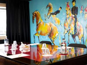 une table en verre avec une peinture de chevaux dessus dans l'établissement Mercure Bords de Loire Saumur, à Saumur