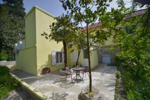 uma mesa e cadeiras em frente a uma casa amarela em Apartment Glorija em Kamenari