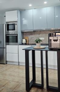 サンタ・ポラにあるMirador de Varaderoの白いキャビネットと鉢植えのテーブル付きのキッチン