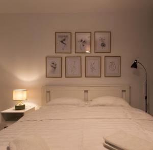 ein Schlafzimmer mit einem weißen Bett mit vier Bildern an der Wand in der Unterkunft Aquarium Apartament in Buzău