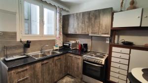 a small kitchen with wooden cabinets and a sink at Villa tusia in Vravrona