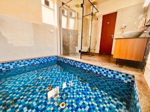 兰纳加The Woods Farmhouse Resort, Jim Corbett - A beautiful wellness resort in the lap of nature的浴室设有蓝色瓷砖的游泳池