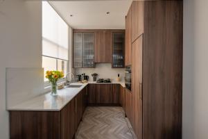 a kitchen with wooden cabinets and a vase of flowers at Charles of Mayfair in London