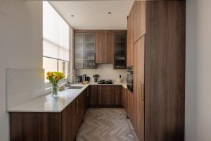 a kitchen with wooden cabinets and a vase of flowers at Charles of Mayfair in London