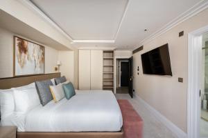 a bedroom with a white bed and a flat screen tv at Charles of Mayfair in London