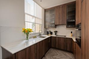 a kitchen with wooden cabinets and a vase of flowers on a counter at Charles of Mayfair in London