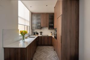 a kitchen with wooden cabinets and a vase of flowers at Charles of Mayfair in London
