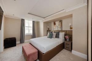 a bedroom with a large bed and a pink stool at Charles of Mayfair in London