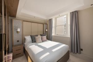 a bedroom with a large bed and a window at Charles of Mayfair in London