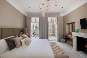 a bedroom with a large white bed and a fireplace at Charles of Mayfair in London
