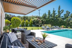 a patio with a table and chairs and a swimming pool at Eunoia Blue Villa Heraklion Crete, Sea View, Private Pool, Prassas, Karteros in Prasás
