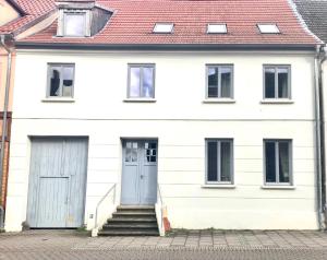 a white house with a blue door and stairs at Stadtnest Malchow - für 2-12 Personen in der Inselstadt - Mecklenburgische Seenplatte in Malchow
