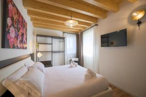 a bedroom with a white bed and a tv at La Còrt Apartments - Number 2 in Manerba del Garda