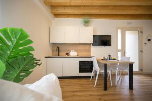 a kitchen with white cabinets and a table with chairs at La Còrt Apartments - Number 2 in Manerba del Garda