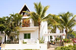 ein weißes Haus mit Palmen davor in der Unterkunft Holiday Aapke Liye Bungalow no 8- 3 BHK in Khopoli