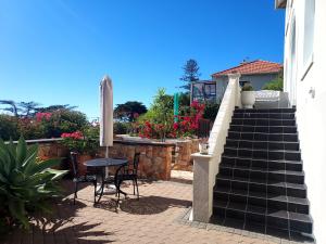 un patio con mesa, sombrilla y escaleras en Penrose House Ocean View Villa, en Muizenberg