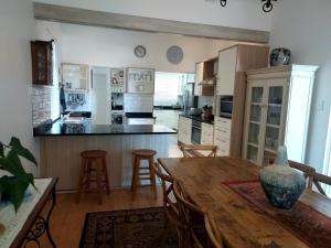 Una gran cocina con una mesa y sillas de madera. en Penrose House Ocean View Villa, en Muizenberg