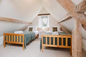 ein Schlafzimmer im Dachgeschoss mit zwei Betten und einem Fenster in der Unterkunft Mulberry Cottage - Stunning 5 Bed in Wiltshire! in Charlton