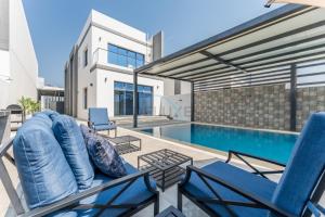 a house with a swimming pool and two chairs at Sea Views 4BR and Assistant's Room Villa with Private Pool, Sharm - Al Dana Villa, Al Dana Island by Deluxe Holiday Homes in Fujairah