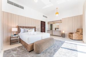 a bedroom with a large bed and a chair at Sea Views 4BR and Assistant's Room Villa with Private Pool, Sharm - Al Dana Villa, Al Dana Island by Deluxe Holiday Homes in Fujairah +47 photos