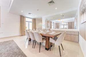 a dining room with a wooden table and white chairs at Sea Views 4BR and Assistant's Room Villa with Private Pool, Sharm - Al Dana Villa, Al Dana Island by Deluxe Holiday Homes in Fujairah