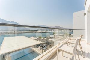 a balcony with a wooden table and chairs on it at Sea Views 4BR and Assistant's Room Villa with Private Pool, Sharm - Al Dana Villa, Al Dana Island by Deluxe Holiday Homes in Fujairah