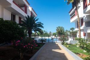 a walkway in front of a building with trees and flowers at El Delfín in Playa de las Americas
