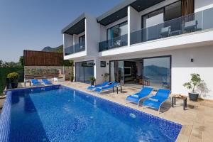 a villa with a swimming pool and blue chairs at Villa Upper House in Kas