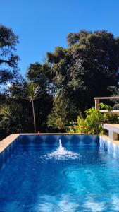 a blue swimming pool with trees in the background at Casa de campo zona rural- wifi - lareira - in Gravataí