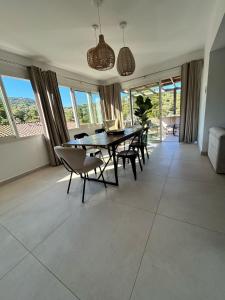 a dining room with a table and chairs and windows at Appartement de standing aux portes de Propriano in Propriano