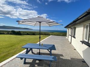 a picnic table with an umbrella on a patio at House Gowlane in Castlegregory