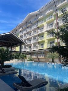 a hotel with a swimming pool in front of a building at Family Suites at the Amani Grand Residences - Mactan Airport in Pusok