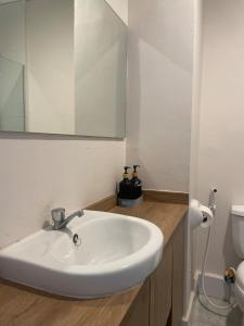 a bathroom with a white sink and a mirror at Family Suites at the Amani Grand Residences - Mactan Airport in Pusok