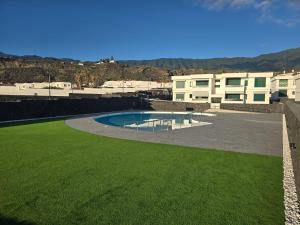 a swimming pool in a yard next to some buildings at VV Milenaiver "by henrypole home" in Los Cancajos
