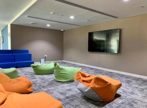 アブダビにあるF1 Dreamstay 1bhk Gym Poolの緑とオレンジ色の枕とテレビのある部屋