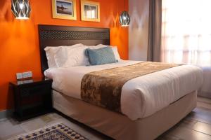 a bedroom with a large bed with an orange wall at Villa de Chazha Guesthouse in Francistown +104 photos