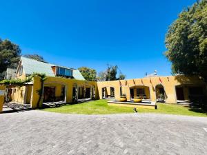 a large yellow building with a bench in the yard at 17 on Bird Guest House in Beaufort West